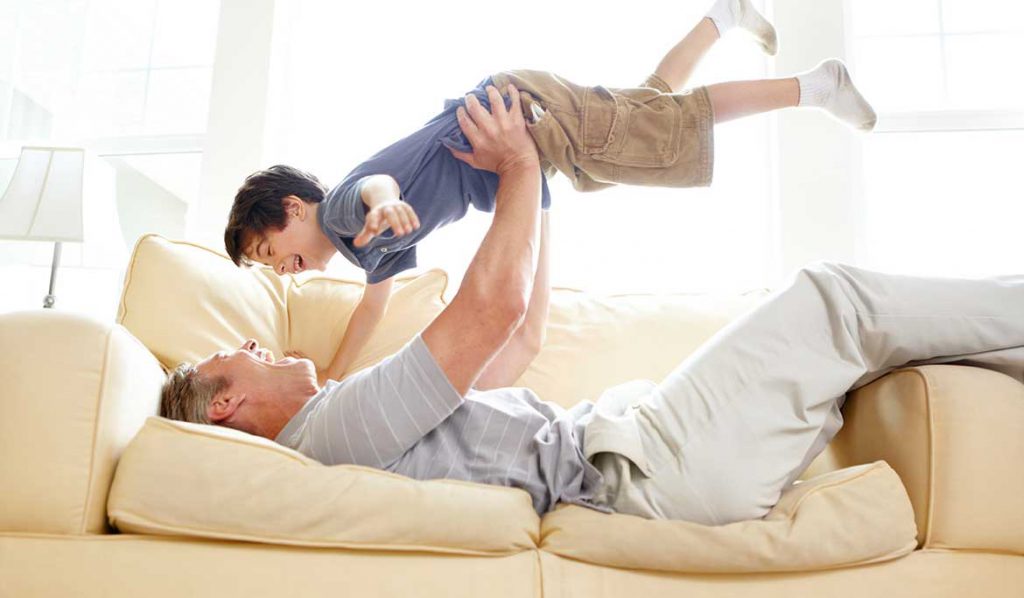 Älterer Mann und Enkel auf Couch mit starker Wirbelsäule